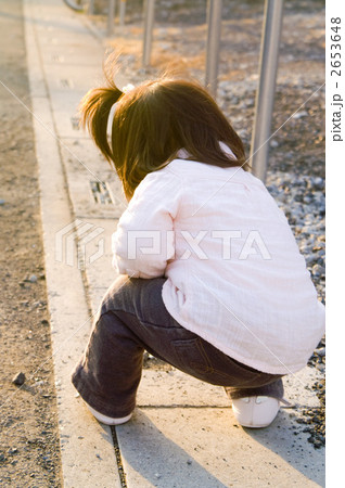 子供 逆光 全身 しゃがむの写真素材