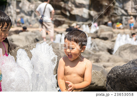 子供 水遊び 女の子 裸 笑顔 水の写真素材