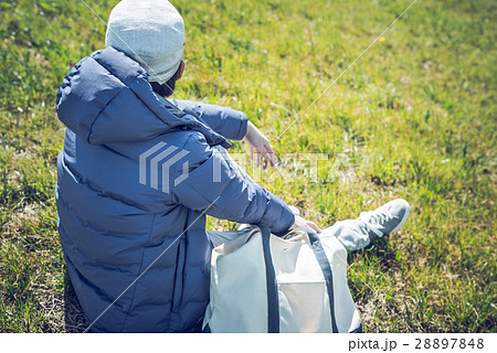 男性 草むら 座る 後ろ姿の写真素材