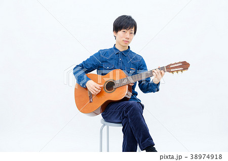 ギター 演奏 座る シャツの写真素材