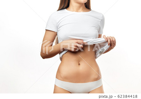 Attractive young woman in white underwear posing against white