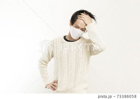 マスク姿の男性/頭痛で頭を抱える/具合が悪い独身男性/	