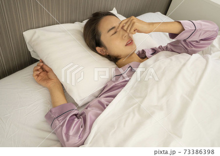 病気で寝込んでいる女性/体調の悪い女性/ベットに寝ている美しい女性