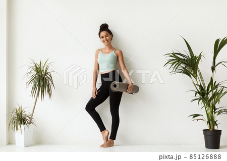 Studio Shot Of Slim Sporty Woman Holding Yoga Mat Before Or After