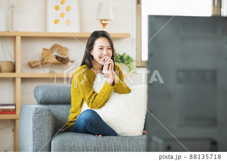 自宅のリビングでTVを楽しむ女性