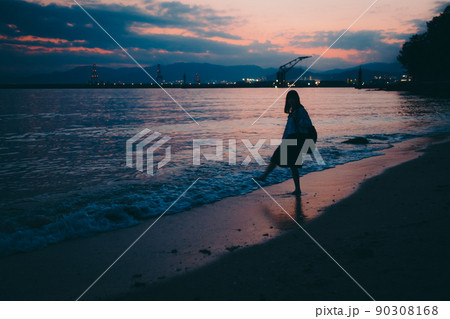 女の子 海 後ろ姿 夕暮れの写真素材