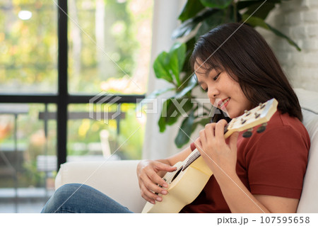 Happy young asian woman with casual clothing playing ukulele