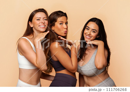 Three cheerful arab, european, latin women in underwear embracing