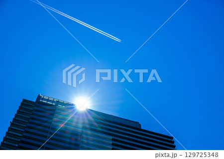 高層マンションの上空を飛ぶ旅客機とひこうき雲